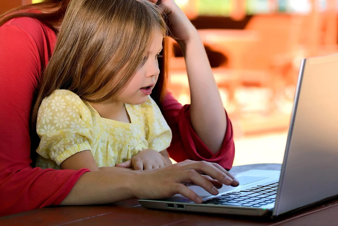 An adult and child looking at a laptop together